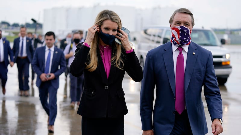 In this July 15, 2020, file photo Sen. Kelly Loeffler, R-Ga., puts on a face mask as she walks...