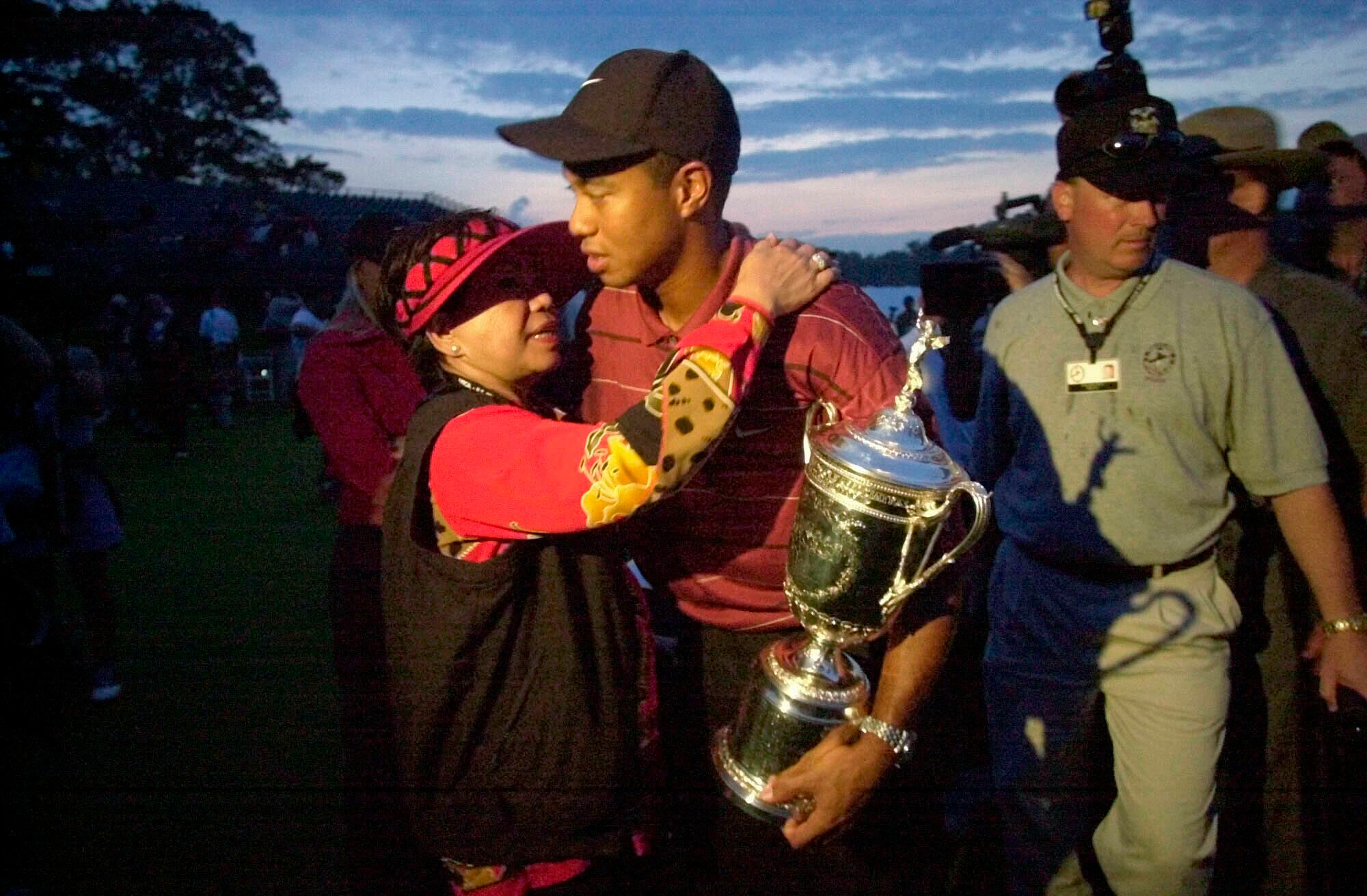 FILE - In this Sunday, June 16, 2002, file photo, Tiger Woods holds his trophy and embraces...