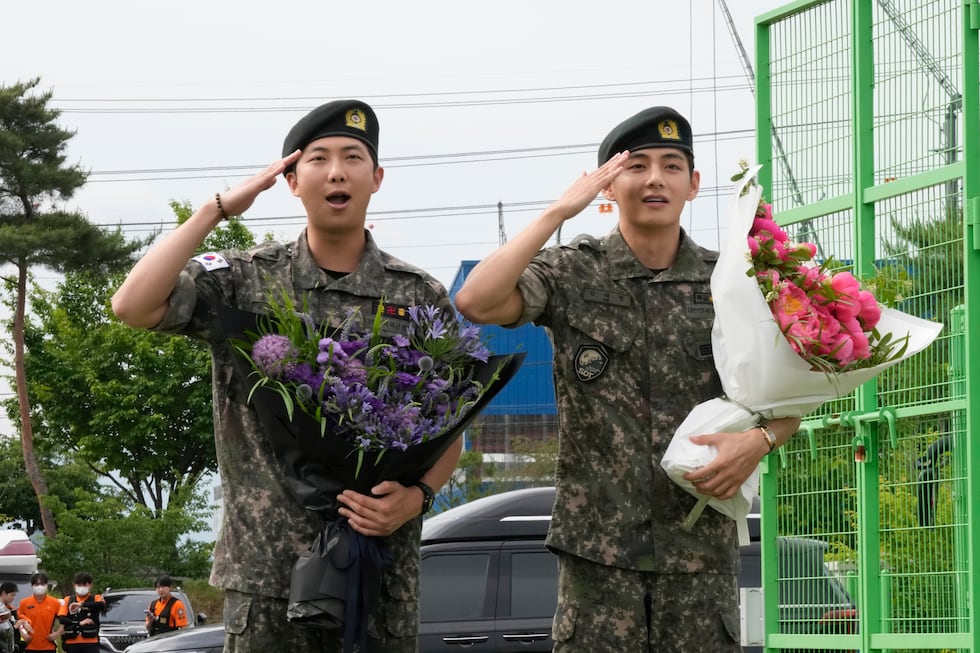 K-pop band BTS RM, left, and V salute after being discharged from a mandatory military...