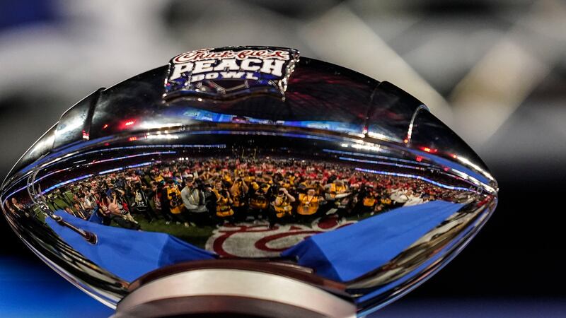 FILE - Photographers are reflected in The George P. Crumbley Trophy after the Peach Bowl NCAA...