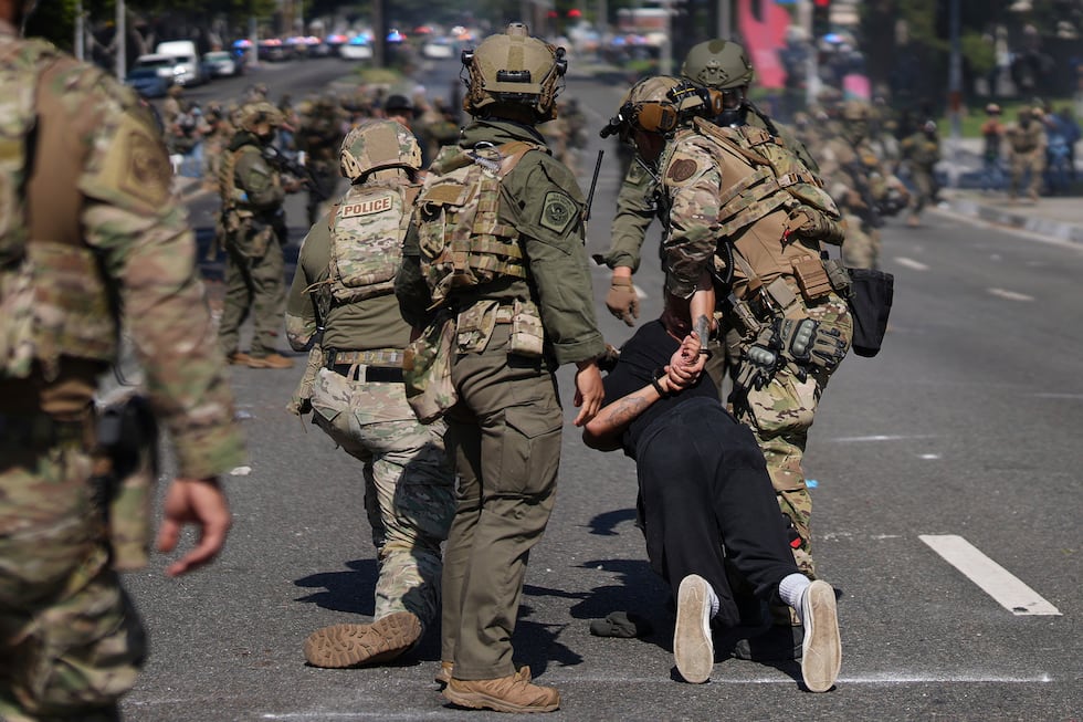 Police detain a man during a protest in the Paramount section of Los Angeles, Saturday, June...