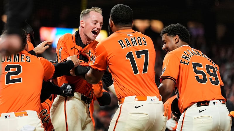San Francisco Giants' Tyler Fitzgerald, center left, is mobbed by teammates after scoring the...