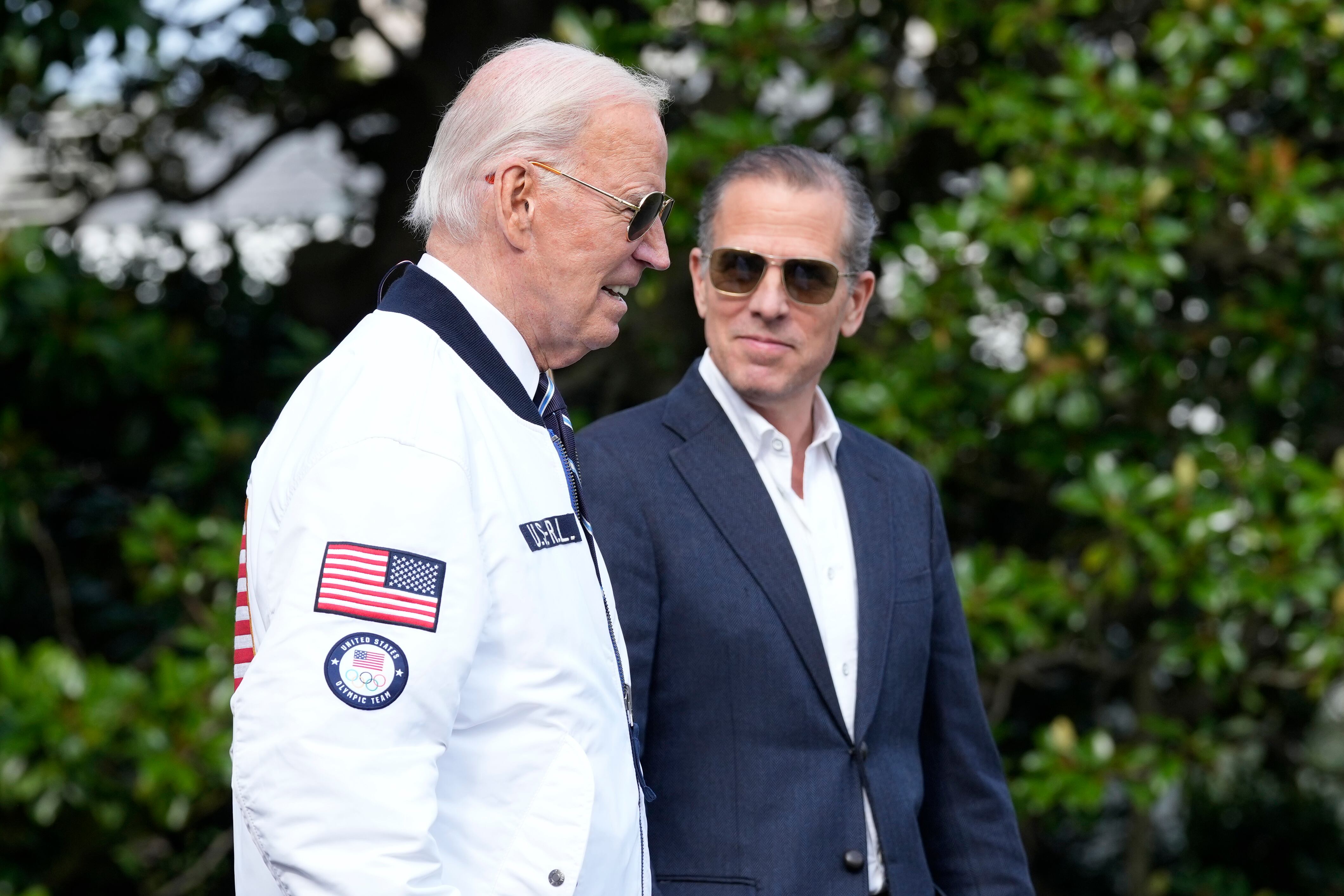 FILE - President Joe Biden, wearing a Team USA jacket and walking with his son Hunter Biden,...