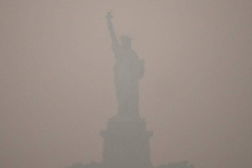 The Statue of Liberty stands during sunset as smoke from wildfires blankets the sky, Thursday,...