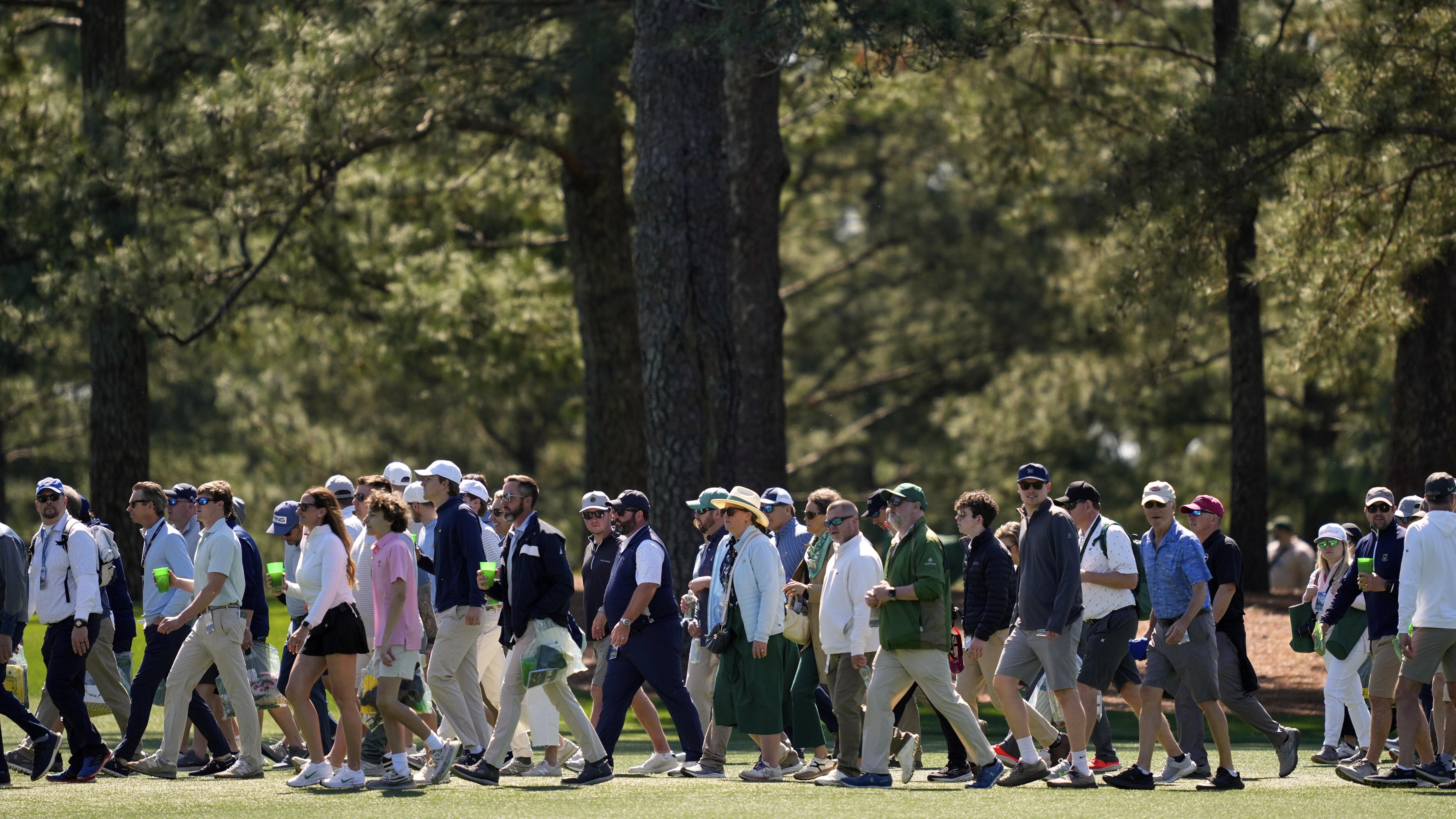 Patrons cross the 15th fairway during a practice round at the Masters golf tournament,...
