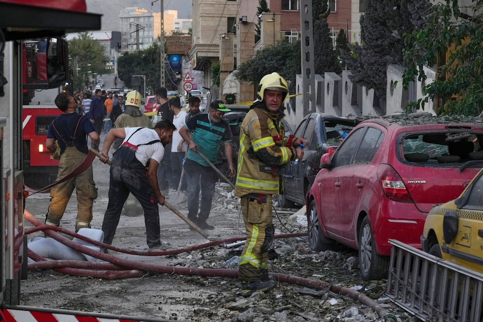 Firefighters and people clean up the scene of an explosion at a residence compound after...