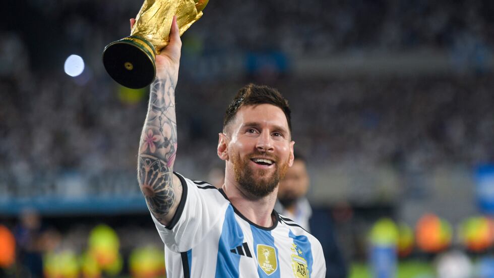 FILE - Argentina's Lionel Messi hoists the winning team replica of the FIFA World Cup trophy...