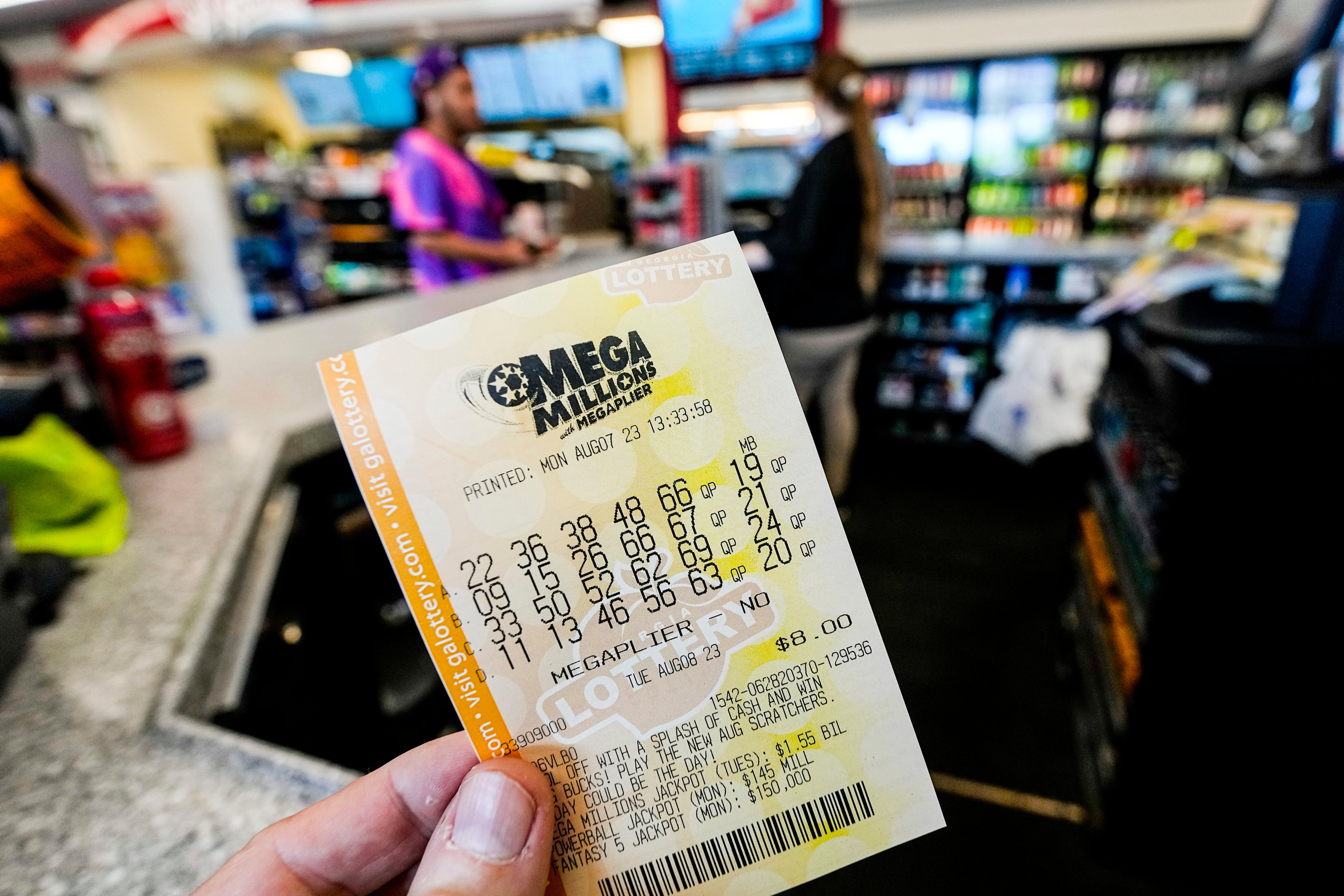 FILE -- A Mega Millions ticket is seen as a person makes a purchase inside a convenience store...