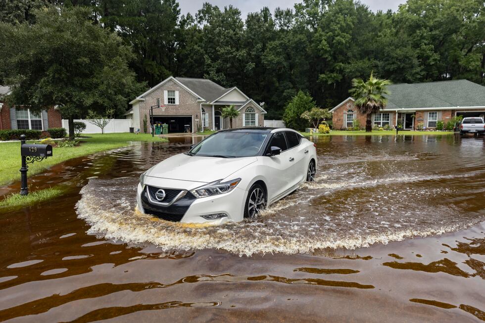 Keon Johnson leaves his house on his way to work down a street that flooded on Monday from...