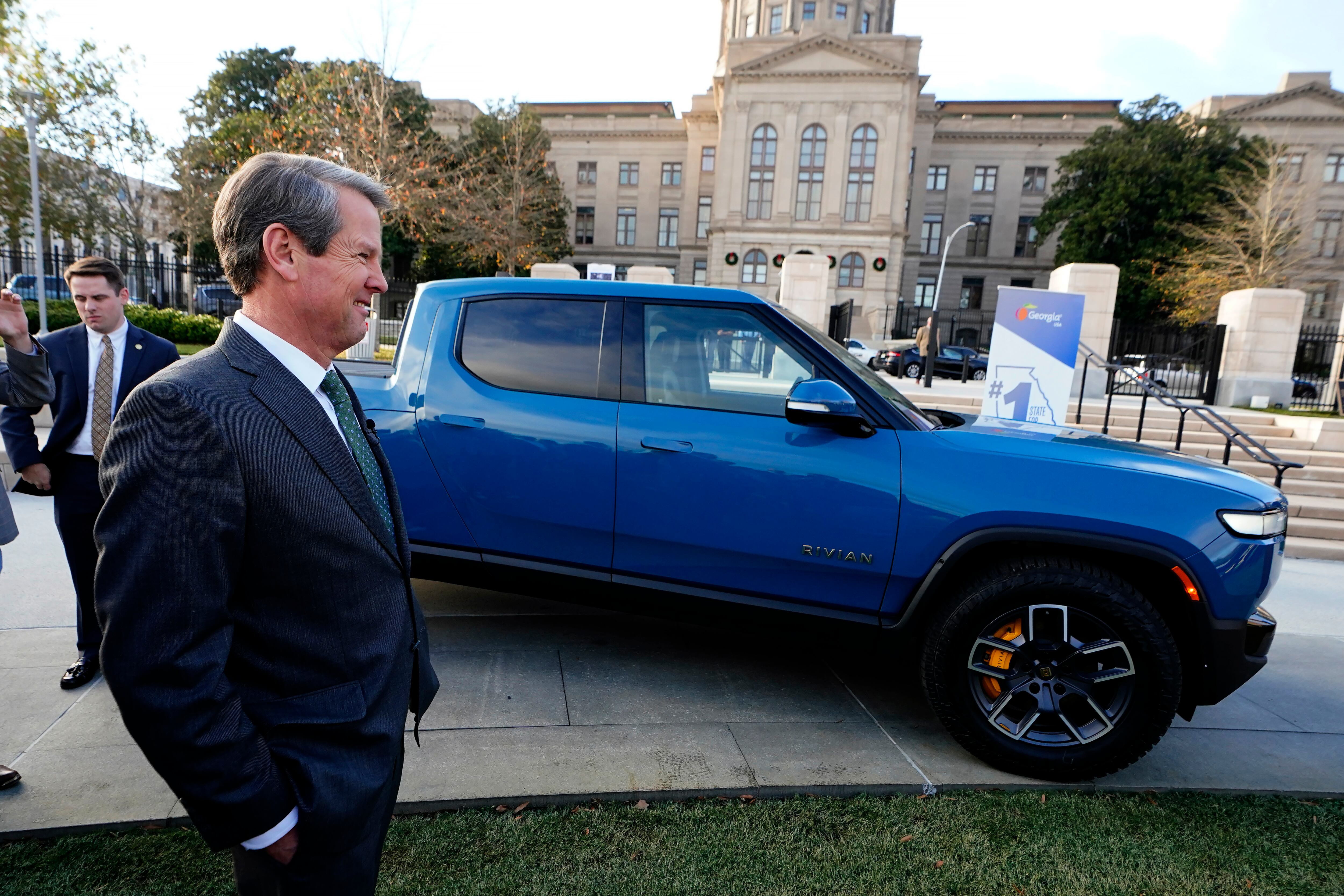 FILE -- Gov. Brian Kemp stands next to a Rivian electric truck while announcing the company's...