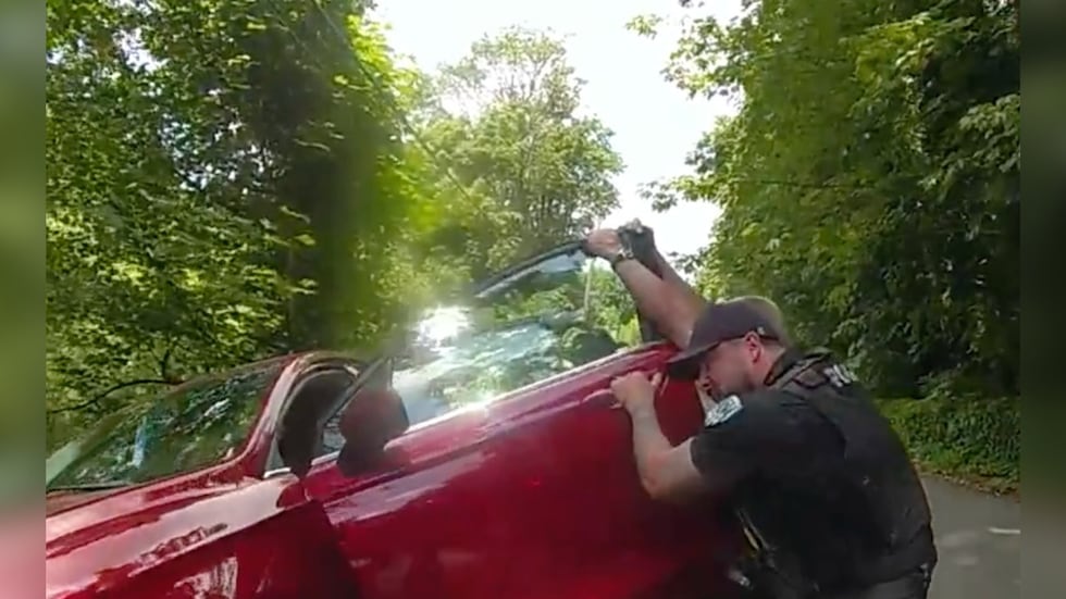 Tukwila Police Department shared a photo of one of its officers grabbing a car to keep it from...
