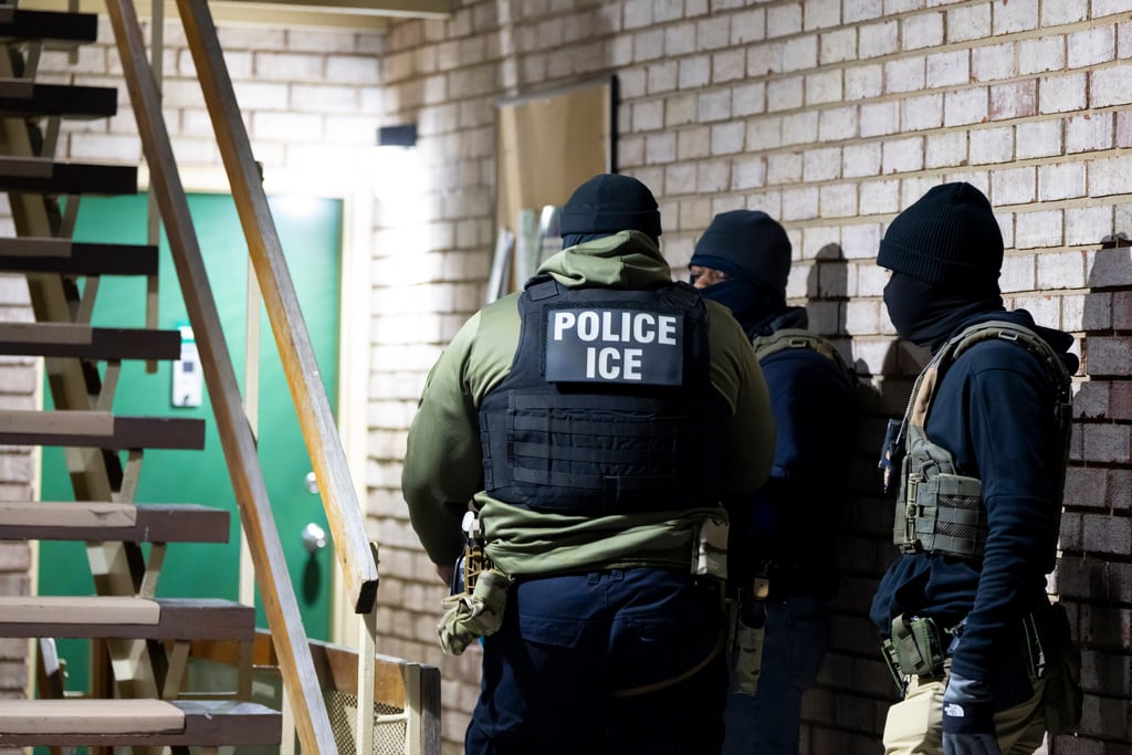 U.S. Immigration and Customs Enforcement officers wait to detain a person Monday in Silver...