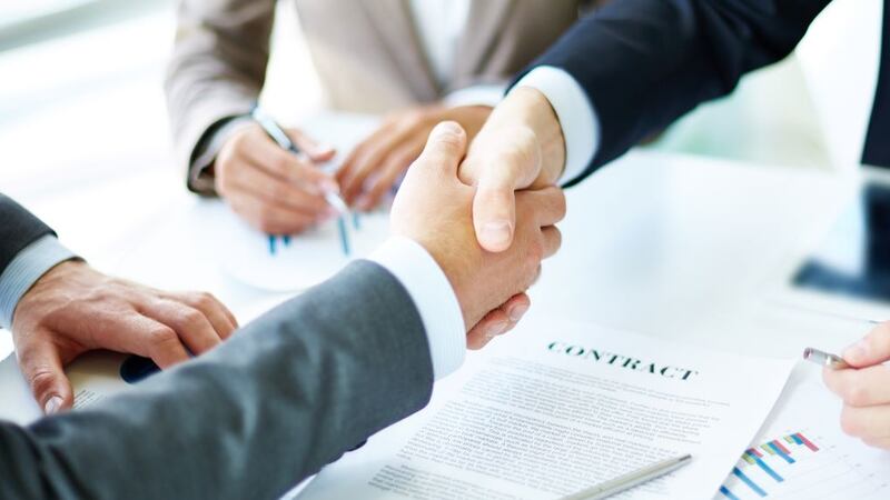 Businessmen shaking hands over a contract.