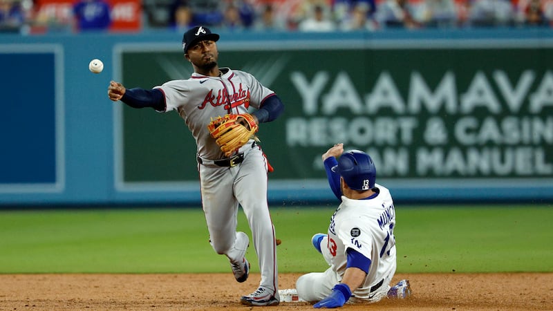 Atlanta Braves' Ozzie Albies, left, turns a double play at second base after forcing out Los...