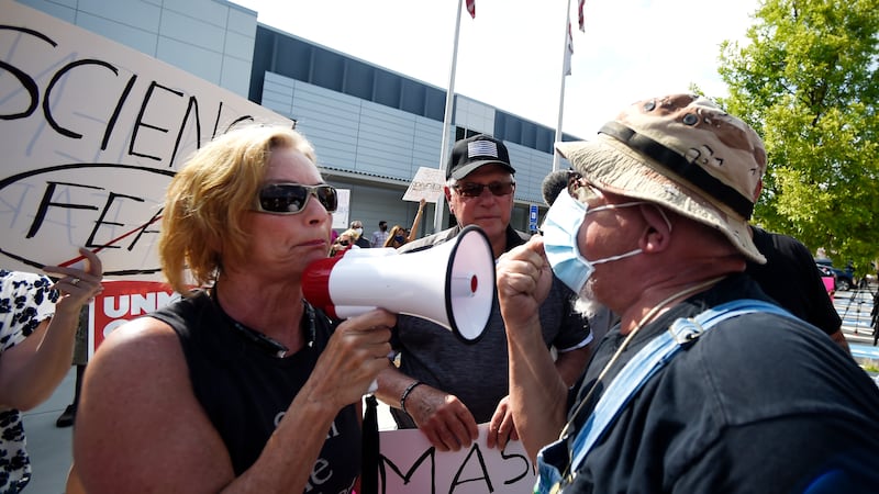 A pro-mask demonstrator, right, speaks with a non-mask demonstrator, left at the Cobb County...