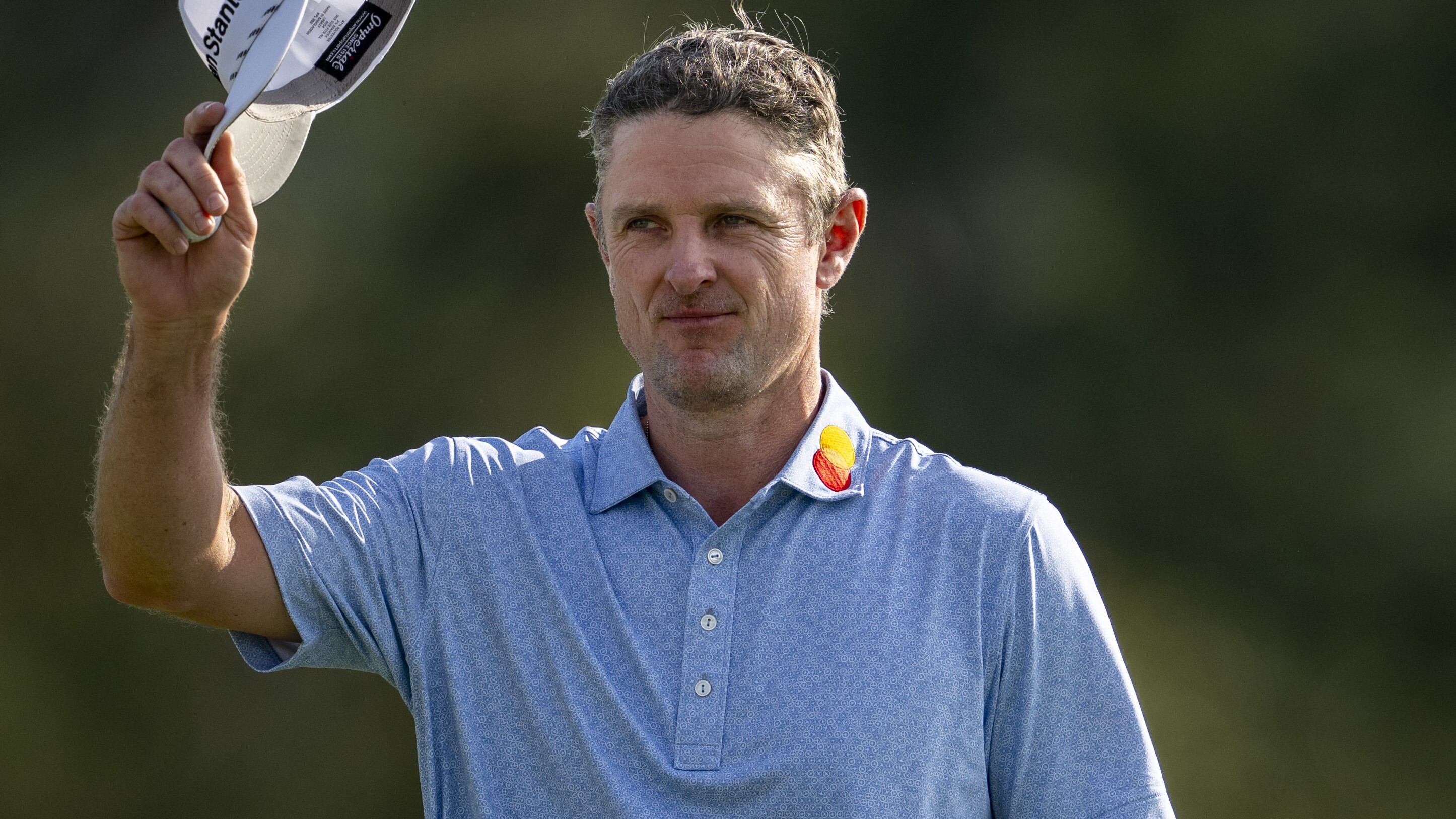 Justin Rose of England tips his hat to patrons on the No. 18 green during the first round of...