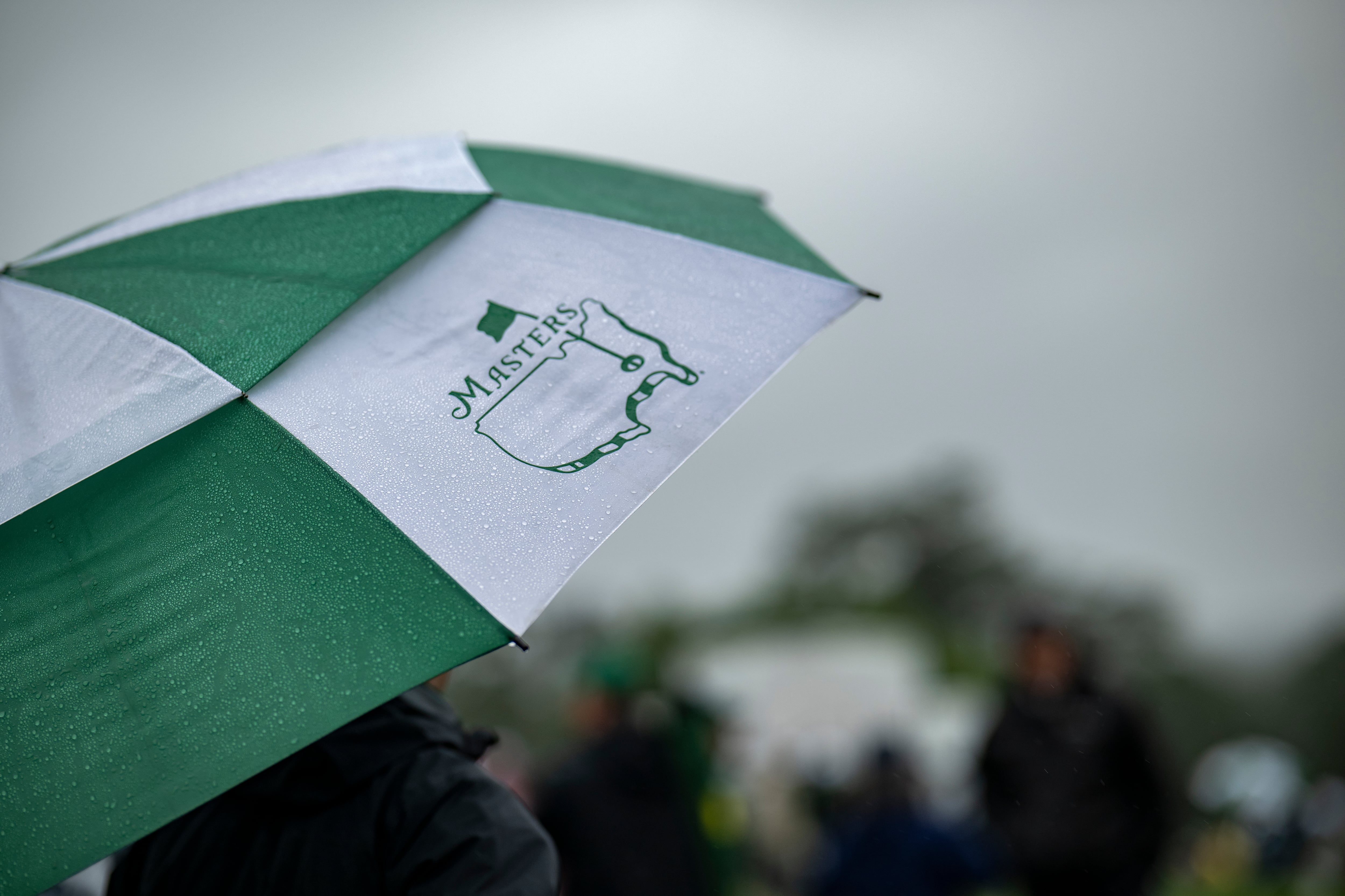Patrons watching from underneath a Masters umbrella during the continuation of the second...