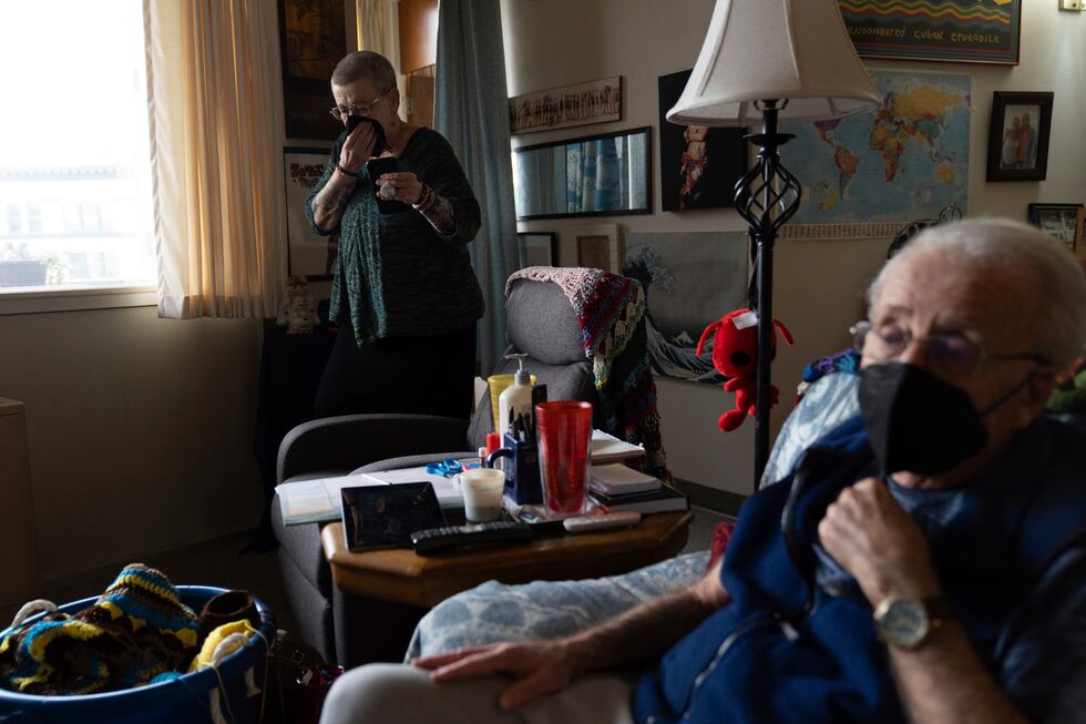 Joan Starr talks on the phone, while Al Hase sits in their living room, at Smith Tower...