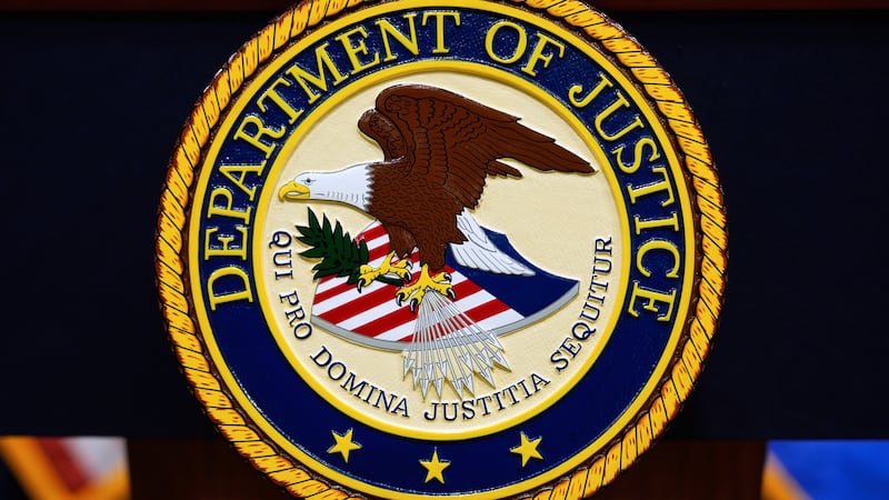The U.S. Department of Justice logo is seen on a podium before a press conference with...